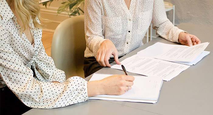 Two women at a conference table looking at a stack of papers